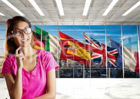 main language flags behind the window. Young happy woman in the office