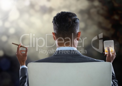 Businessman Back Sitting in Chair with cigar and drink glass with bokeh sparkling lights