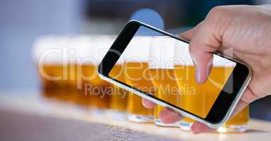 Hand taking picture of beer glasses through smart phone