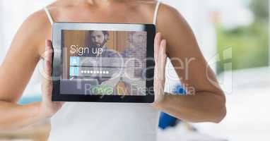 Midsection of woman showing sign up page on digital tablet