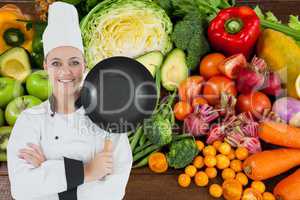 Chief with frying pan against vegetable background