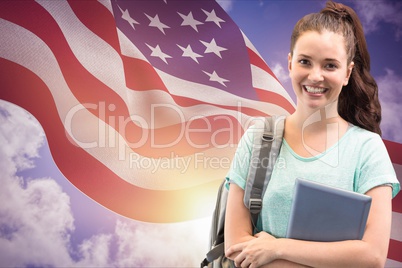 students carrying a bag is holding notebook against American flag