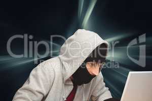 Hacker hiding his face and using a laptop against dark background