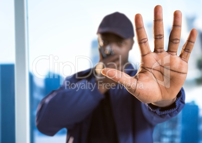 Security guard with walkie talkie and hand in front against blurry window showing city