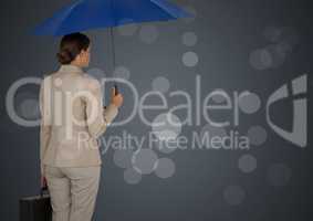 Back of business woman with umbrella and briefcase against grey background and bokeh