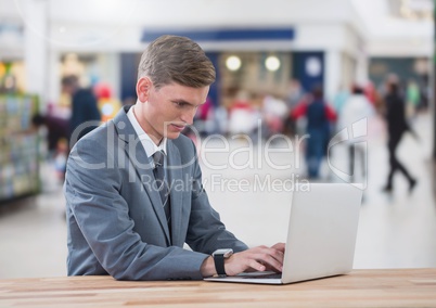 Businessman on laptop in shopping mall