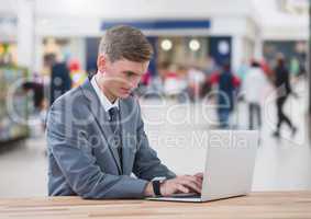 Businessman on laptop in shopping mall
