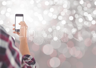 Hand holding mobile phone with sparkling light bokeh background