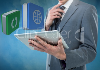 Businessman holding tablet with apps icons against blue foggy background
