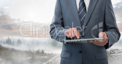 Businessman holding tablet outside in landscape