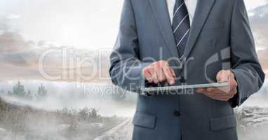 Businessman holding tablet outside in landscape