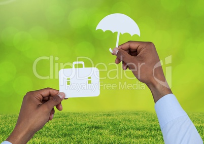 Cut outs of Briefcase and umbrella insurance over grass