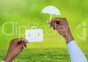 Cut outs of Briefcase and umbrella insurance over grass
