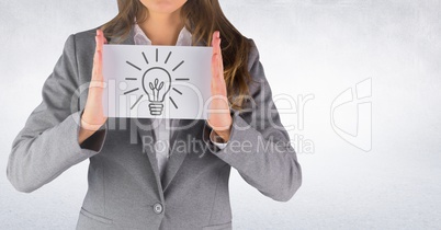 Business woman mid section with card showing grey lightbulb graphic against white wall