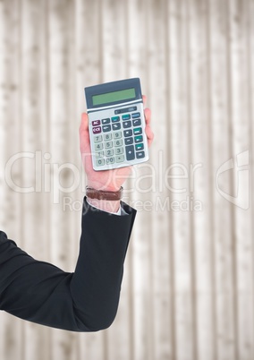 Hand with calculator against blurry wood panel
