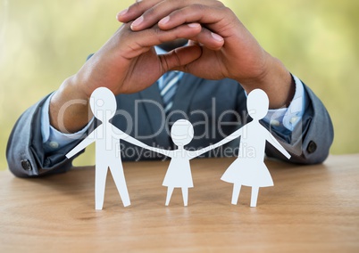 Cut outs of family under protective hands with green nature