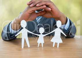 Cut outs of family under protective hands with green nature
