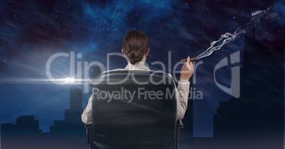 Businesswoman seated in a chair smoking and watching the town during the night