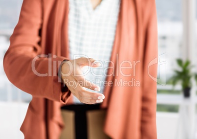 woman with orange blazer giving hand to handshake in her office