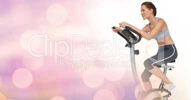 Young woman doing exercise bike with pink background