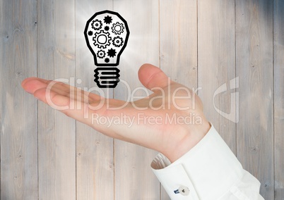 Hand with cogs in lightbulb graphic and flare against grey wood panel
