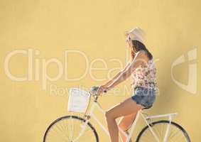 Casual woman with straw hat biking with yellow background