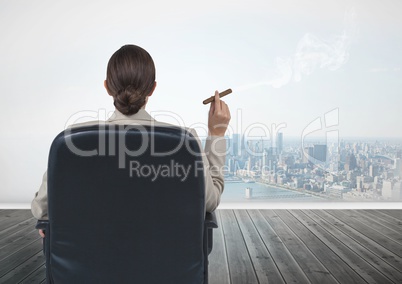 Rear view of businesswoman sitting on chair and smoking cigar while looking at city
