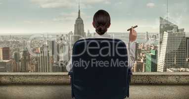 Rear view of businesswoman sitting on chair and looking at city while smoking cigar