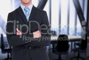 businessman crosses his arms against office background