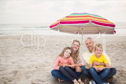 Happy family at the beach under a colored parasol