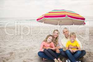 Happy family at the beach under a colored parasol