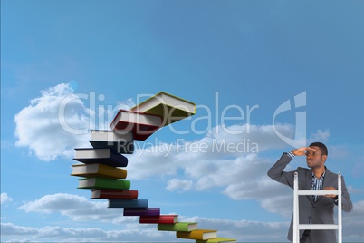 Businessman on ladder watching far away close to a book stairs
