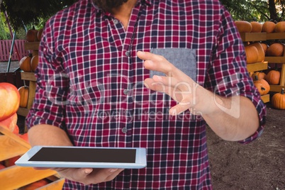 Farner is holding a tablet computer against pumpkin storage background