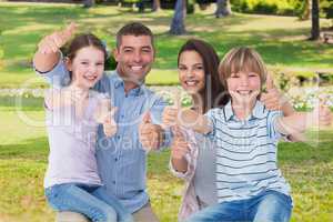 Happy family with thumbs up on garden