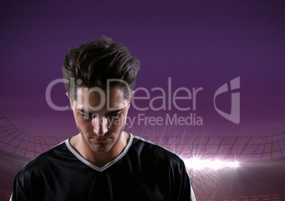 soccer player looking down, purple field lights background