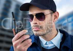 Serious security guard with glasses and walkie-talkie with a blurred building background