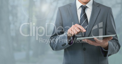 Businessman holding tablet and grey trees