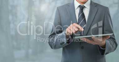 Businessman holding tablet and grey trees