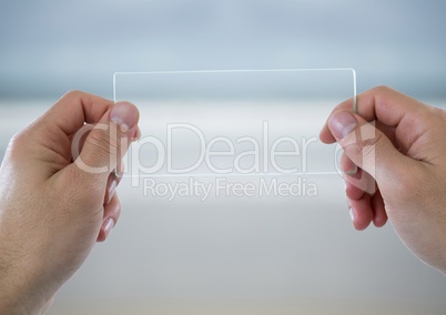 Hands with glass device against blurry beach