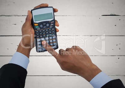 Hands with calculator against white wood panel
