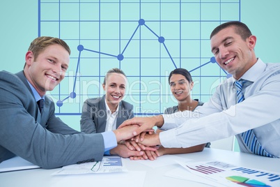 Business workers gather their hands together during a meeting in front of digital screen with graphi