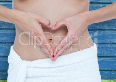 fitness: woman doing hearth with her hands on her belly with blue wood background