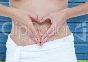 fitness: woman doing hearth with her hands on her belly with blue wood background