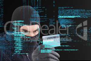 Cyber criminal wearing a hood is holding a credit card against matrix digital rain background