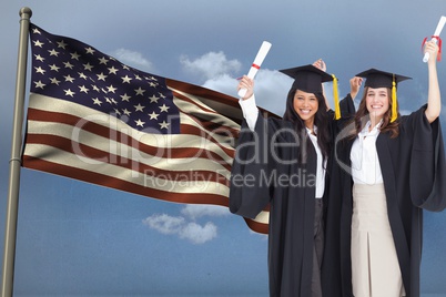 students wearing a robe hire show diploma in front of the american flag against sky background
