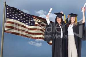 students wearing a robe hire show diploma in front of the american flag against sky background