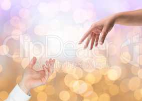 Hands reaching for eachother helping with sparkling light bokeh background