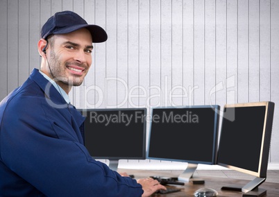 Security guard smiling in front of the computers with white wood background