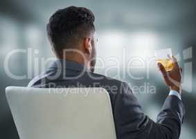 Back of seated business man drinking in blurry grey office