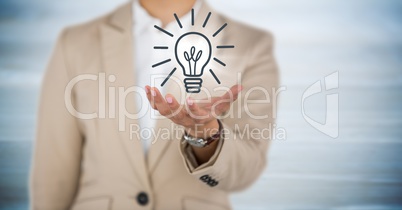 Business woman mid section with hand out and lightbulb graphic with flare against blurry blue wood p